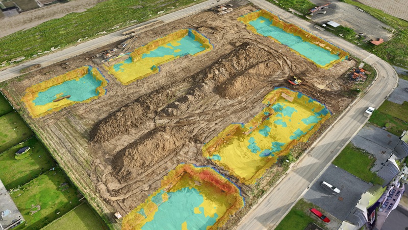 Aerial view of a construction site with color-coded topographical mapping overlays.