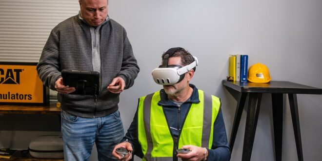 Worker using CAT simulator training with VR headset and controllers in a construction environment.
